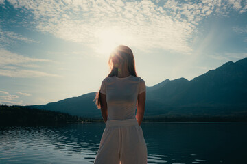 Woman near the water with mountains in the distance during the daytime