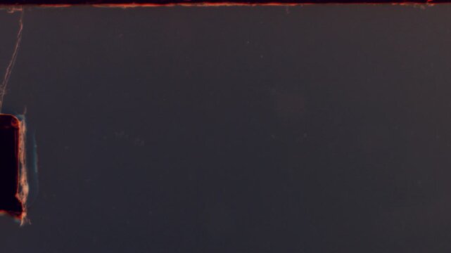 Retro super 8 film strip with light grain, soft red glow on edges and analog dust artifacts