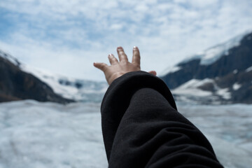 Reaching out towards icy mountain and sky, a hand extends in the frozen air