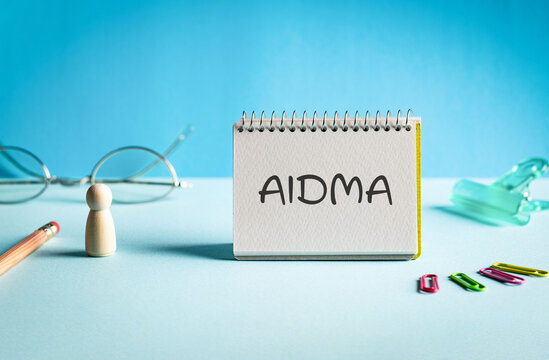 There is notebook with the word AIDMA. It is an abbreviation for Attention, Interest, Desire, Memory, Action as eye-catching image.