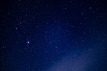 Stunning night sky with stars and shooting stars over dark horizon