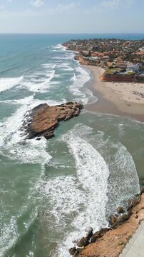 Aerial drone footage of Cala Capit&aacute;n in Cabo Roig, Orihuela Costa, Alicante, Spain. Scenic
Mediterranean beach with a small island offshore, turquoise waters and rocky shoreline,