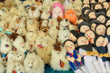 Stuffed llamas toys and rag dolls of men in traditional clothing at the Plaza de los Panchos craft market in Otavalo, Imbabura province, Ecuado