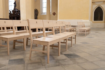 Wooden benches arranged in a spacious interior, featuring soft lighting and a serene atmosphere, perfect for contemplation and reflection in a tranquil setting