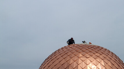 The worker who is climbing the golden dome of the mosque to repair it so that it becomes even more...