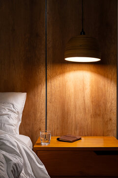 Bedside table with warm lamp glow, glass of water and notepad