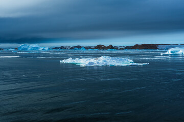 Winter natural background with fragments of blue ice and heaps of pieces of ice floes on a sunny frosty day. Abstract cold background, mock up. Harsh lifeless environment