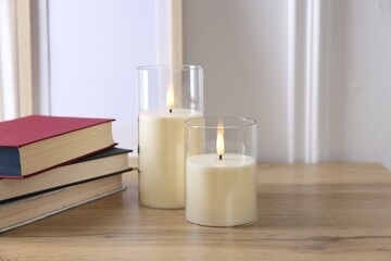 Decorative LED candles and books on wooden table indoors