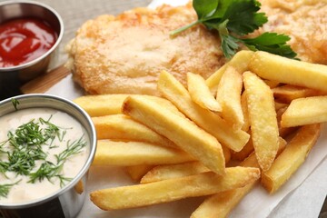 British Traditional Fish and chips served with sauces on table, closeup