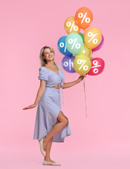Woman holding balloons with percent signs on pink background. Discount offer