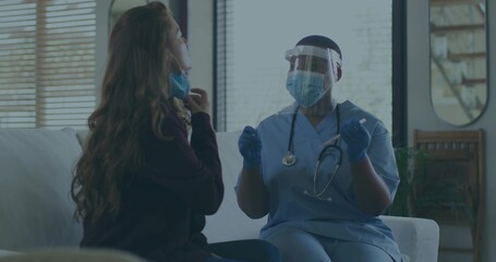 Sitting nurse in scrubs consulting patient adjusting mask in living room, with stethoscope, gloves