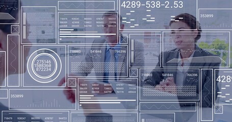 Analyzing business team interacting with digital data panels at conference table in meeting room