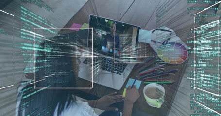 Writing designer jotting note at desk during call, with laptop, supplies, code overlays, copy space