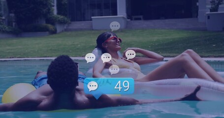 Couple reclining on yellow inner tube and clear mattress in backyard pool, red sunglasses, swimwear