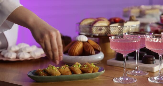 Pastry chef decorating delicious baklava at buffet table, closeup