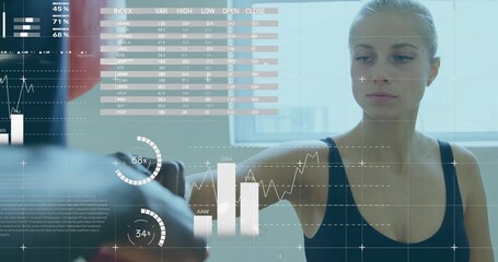 Training woman wearing sports bra punching focus mitt in gym studio, with overlaid data charts