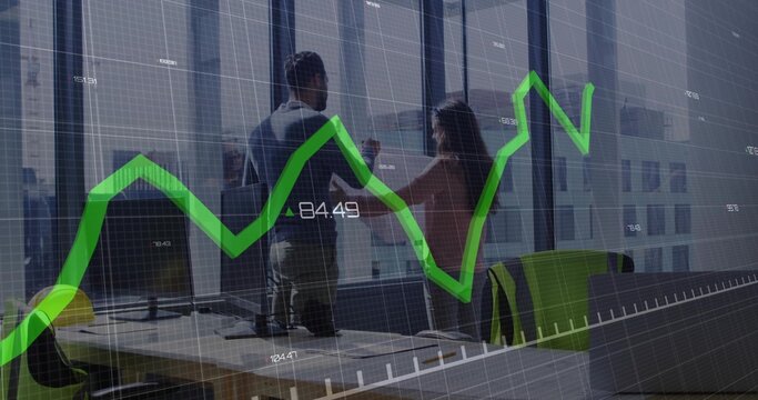 Colleagues holding tablet, pointing at green chart on office windows, with monitors and safety gear