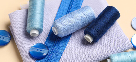 Threads and sewing supplies on beige background, closeup