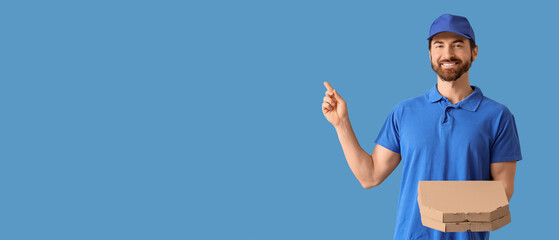 Male courier with pizza boxes pointing at something on blue background
