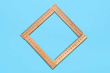 Frame made of wooden rulers on blue background