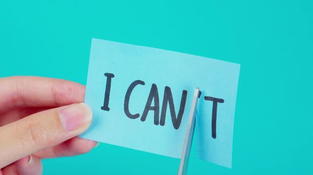 Transforming limitations into possibilities with scissors cutting 'I CAN'T' into 'I CAN' isolated on blue background