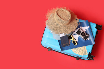 Suitcase with travelling belongings, camera and word map on red background