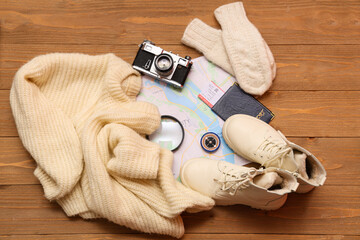 Travelling belongings with sweater, shoes and city map on wooden background