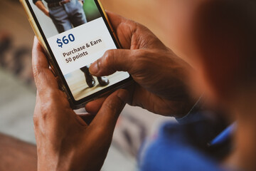 Customer loyalty program concept in e-commerce for customer engagement. Man holding phone displaying earning points after purchasing online.