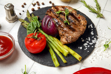 Tasty grilled steak with vegetables and ketchup on white tile background