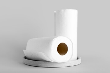 Plate with rolls of paper towels on grey background