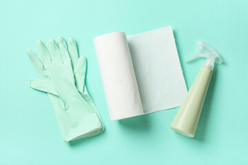 Roll of paper towels with detergent and rubber gloves on turquoise background