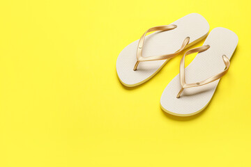 Beige flip-flops on yellow background