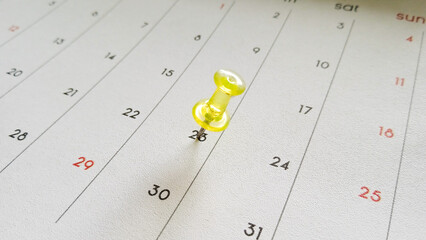 Close-up of a thumbtack pinning the 23rd on a calendar. Calendar page background