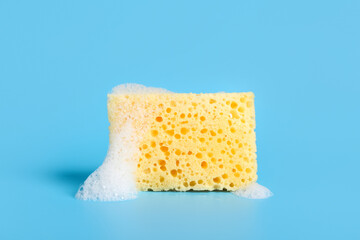 Yellow cleaning sponge with foam on blue background