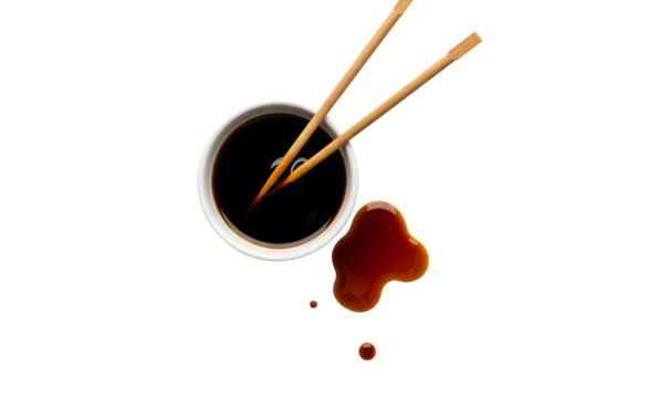 Soy sauce in a white ceramic bowl on a white surface, viewed from above, with wooden chopsticks beside it. Some soy sauce has spilled out.