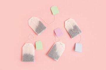 Tea bags with colorful labels on pink background