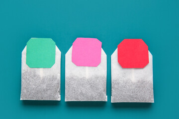 Tea bags with colorful labels on turquoise background