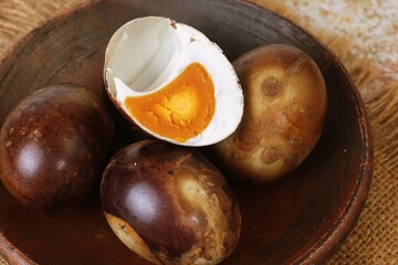 Obraz premium Close Up View of Traditional grilled salted egg or telur asin bakar with dark brown shell and rich orange yolk served on rustic plate. 