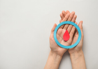 Woman holding blue ring and blood drop on grey background