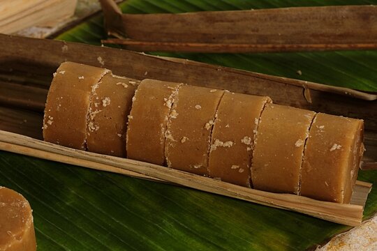 Rolled palm sugar or gula aren placed on banana leaf, traditional Indonesian sweetener, rustic and organic food concept.