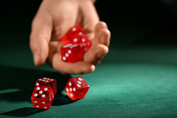 Female hand with red game dices on green background