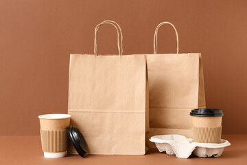 Paper bags with coffee cups on brown background