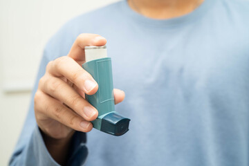 Asthma and chronic obstructive pulmonary disease COPD, Asian young man using metered dose inhaler MDI.