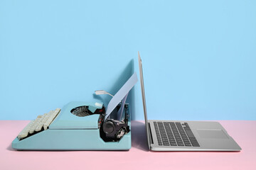 Vintage typewriter with blank paper sheet and laptop on color background
