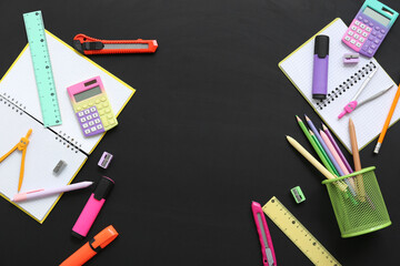 Frame made of different stationery supplies on black chalkboard