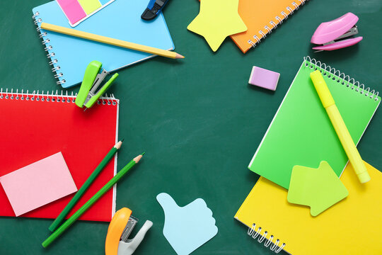 Frame made of different stationery supplies and notebooks on green chalkboard - Powered by Adobe