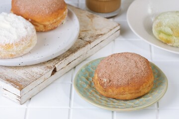 Indonesian style milk donut with vanilla milk powder topping on white plate, delicious homemade dessert bread snack.