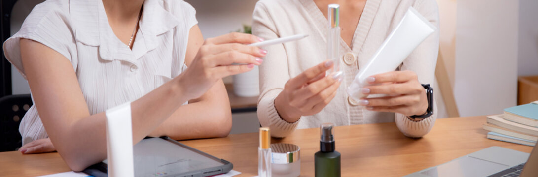 Two asian businesswoman testing and researching cosmetic product or cream in bottle in office, two business woman creative with planning project design package of skincare, development and business.