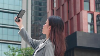 Young asian businesswoman talking and video call with smartphone in urban city, business woman using technology for remote work and communication, online connection or social media and digital career. - Powered by Adobe