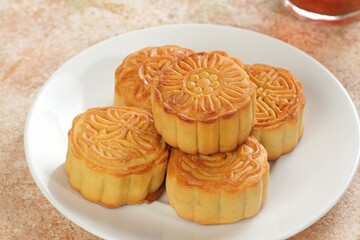 Stacked Chinese mooncakes on white plate, symbol of reunion and happiness during Mid-Autumn Festival. Perfect for Asian food concept.